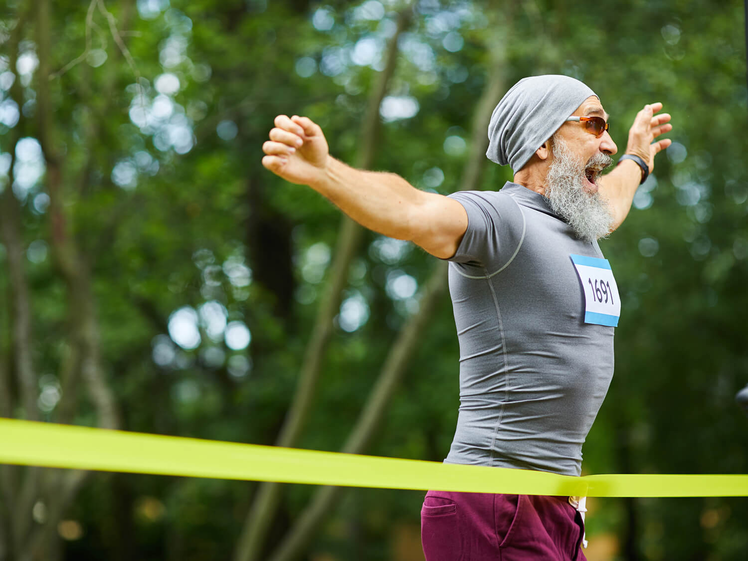 A man ealted as he crosses the finsish line at a running event 