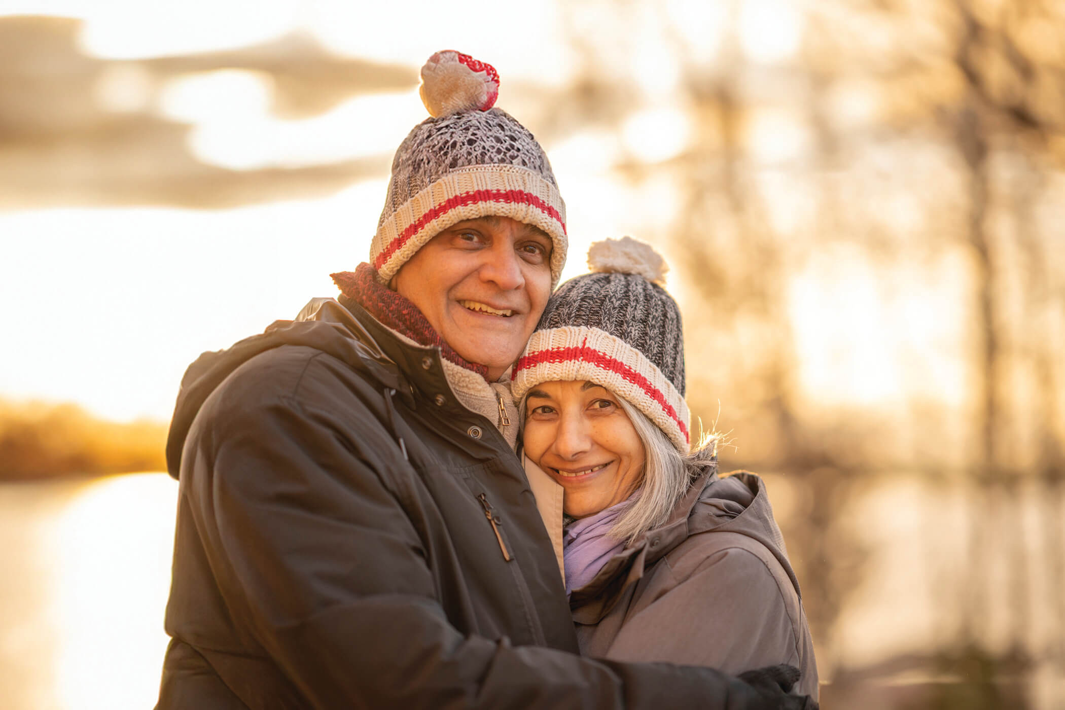 A middle aged couple in each others arms while the sun goes down