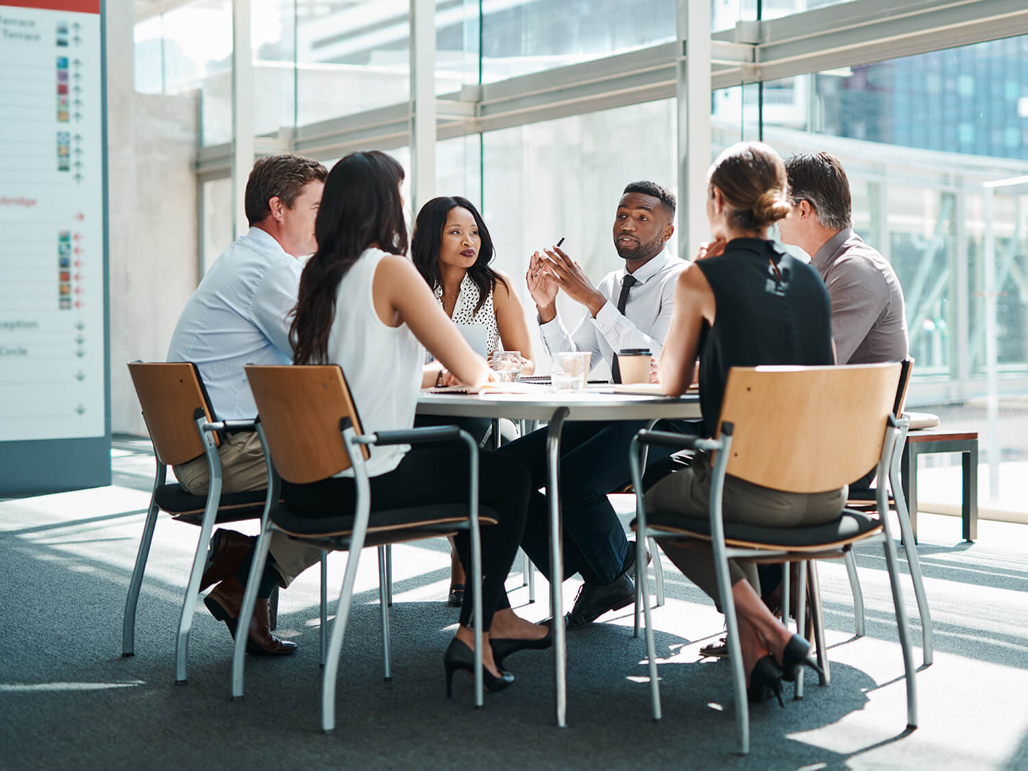 a group of 6 people at a business meeting taking place in a bright modern office 
