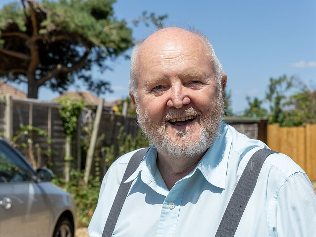 Portrait of Ray, who uses Royal Voluntary Service transport services standing in front of a car 
