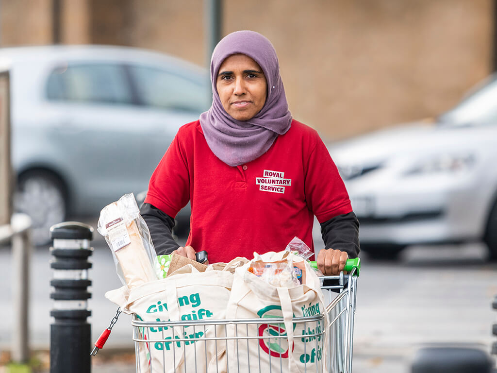 A volunteer pushing a trolley of shopping to deliver to someone in their home